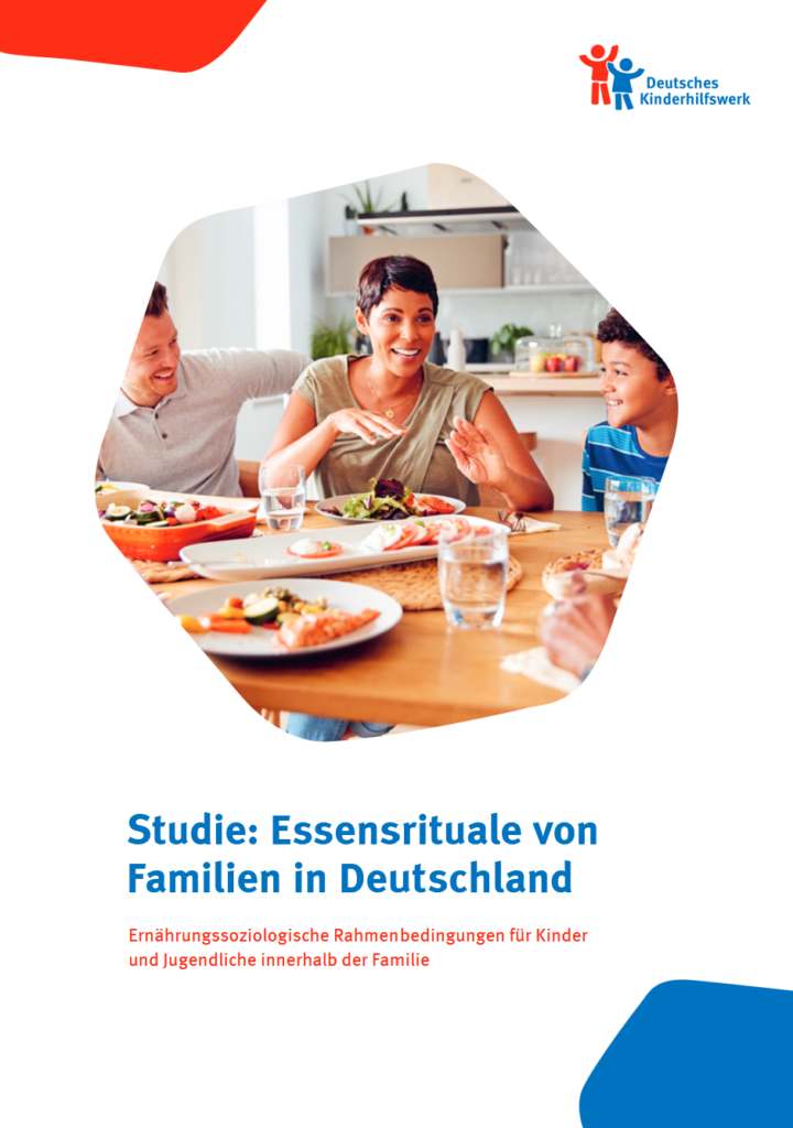Eine Familie sitzt zusammen beim Essen am Tisch und lacht über etwas.