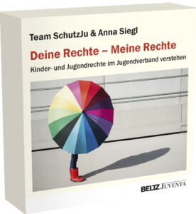 Ein junger Mensch mit roten Gummistiefeln und einem bunten Regenschirm.